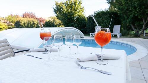 a table with wine glasses on it next to a pool at Logis Murtel in La Mure