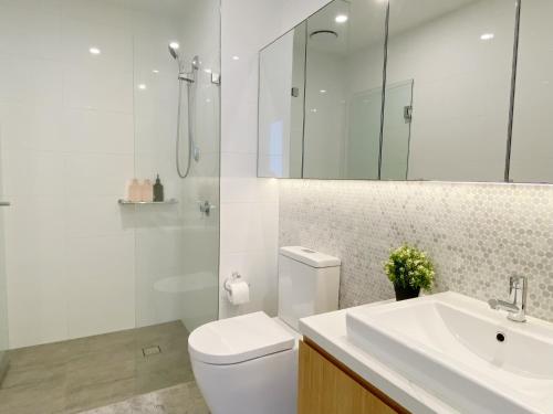 a white bathroom with a toilet and a sink at Cozy 2B2B Apartment with Free Parking & Penthouse Pool in Box Hill