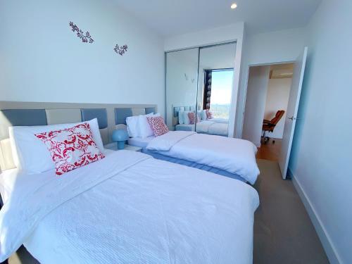 a bedroom with two beds and a mirror at Cozy 2B2B Apartment with Free Parking & Penthouse Pool in Box Hill