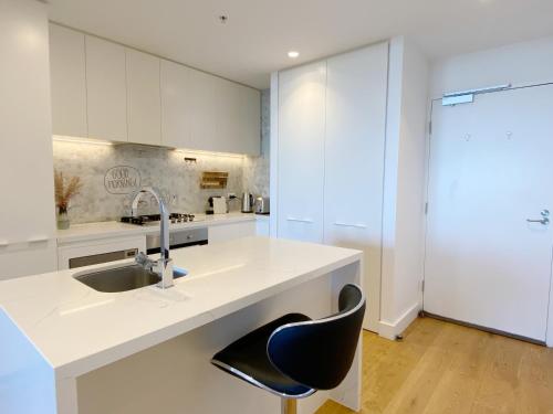 a white kitchen with a sink and a black chair at Cozy 2B2B Apartment with Free Parking & Penthouse Pool in Box Hill