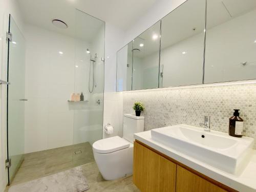a bathroom with a sink and a toilet and a mirror at Cozy 2B2B Apartment with Free Parking & Penthouse Pool in Box Hill