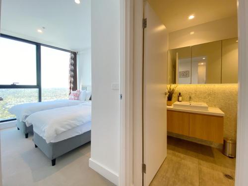 a bedroom with a bed and a sink and a mirror at Cozy 2B2B Apartment with Free Parking & Penthouse Pool in Box Hill