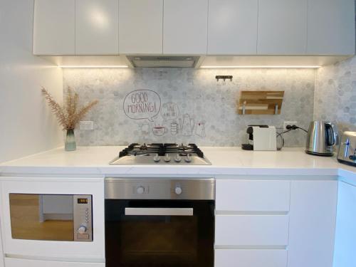 a kitchen with white cabinets and a stove top oven at Cozy 2B2B Apartment with Free Parking & Penthouse Pool in Box Hill