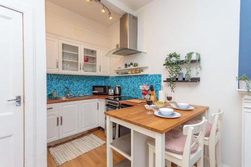 une cuisine avec des placards blancs et une table en bois dans l'établissement Warm 1bed Flat Leith Walk, à Édimbourg