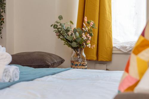 a vase of flowers sitting on top of a bed at Warm 1bed Flat Leith Walk in Edinburgh