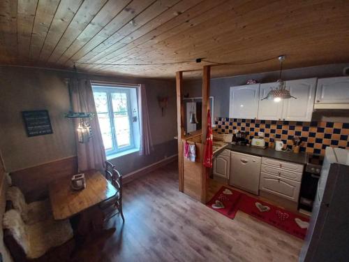 a kitchen with a wooden ceiling and a table at Gite de l'Ours in Saint-Maurice-sur-Moselle