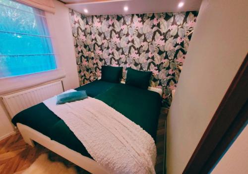 een kleine slaapkamer met een groen bed met bloemenbehang bij "De Jungle" Chalet met veranda op IJsselheide Hattemerbroek Veluwe in Hattemerbroek