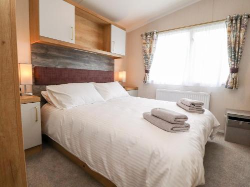 um quarto com uma cama branca e toalhas em 31 Willows em Skipton