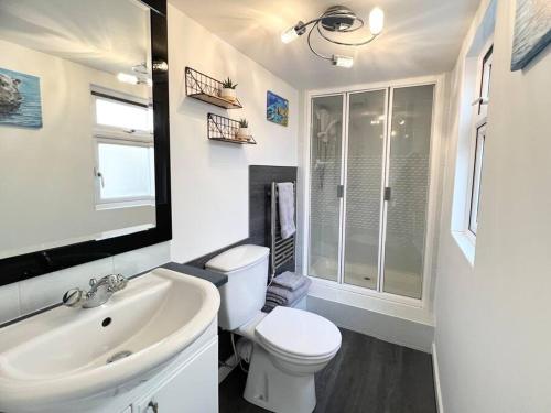 Baño blanco con aseo y lavamanos en Tumbleweed 2 en Dorchester