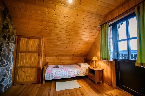 a bedroom with a bed in a wooden cabin at Sokolisko - domki całoroczne z kominkiem in Wysoczany