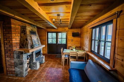 a living room with a stone fireplace and a table at Sokolisko - domki całoroczne z kominkiem in Wysoczany