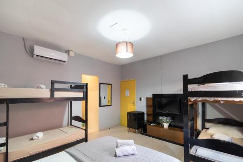 a room with three bunk beds and a television at HMG - Praia de Botafogo in Rio de Janeiro