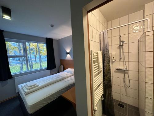 a small room with a bed and a shower at Hótel Austur in Reyðarfjörður