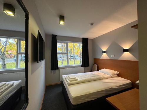 a bedroom with two beds and two windows at Hótel Austur in Reyðarfjörður