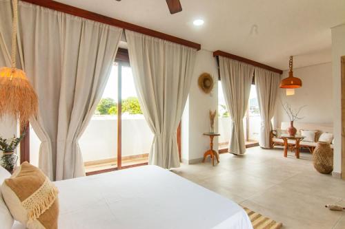 a bedroom with a white bed and large windows at Hotel Boutique de playa - Casa Solhu in Santa Marta