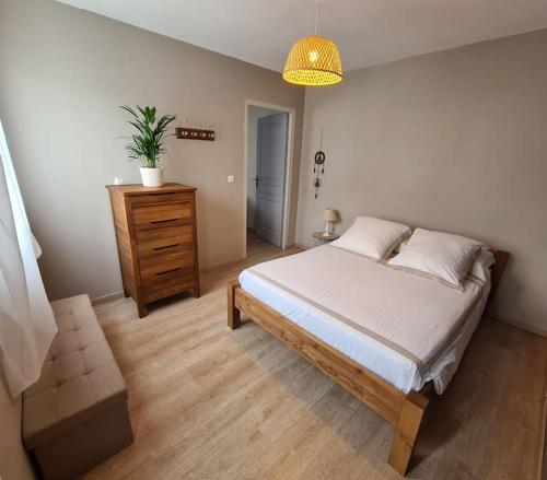 a bedroom with a large bed and a wooden dresser at Dépendance T3 in Aumes