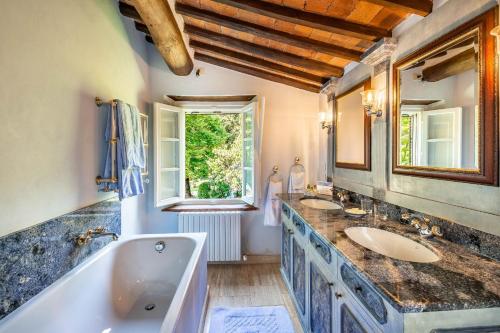 La salle de bains est pourvue de 2 lavabos, d'une baignoire et d'un miroir. dans l'établissement Villa Igea, à Mastiano