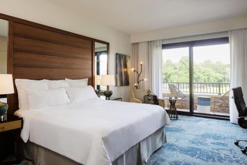 a hotel room with a large bed and a balcony at The Woodlands Resort, Curio Collection by Hilton in The Woodlands