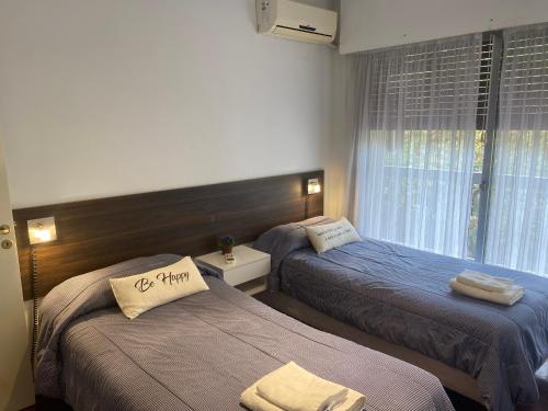 two beds in a hotel room with a window at Alquiler cálido departamento en el corazon mendocino in Mendoza
