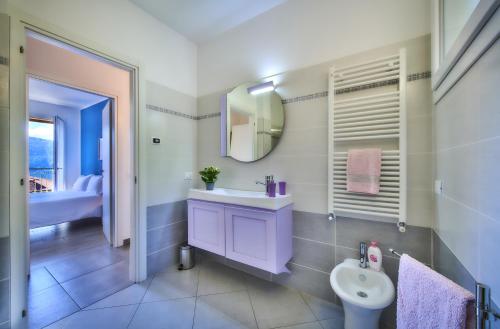 bagno con lavandino viola e specchio di Welcome Home Apartment a Lierna