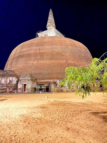 a large building on a beach with a tree at ARANI HOMESTAY in Polonnaruwa