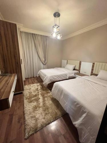 een hotelkamer met 2 bedden en een kroonluchter bij دوبلكس بيفرلي هيلز اربع غرف الشيخ زايد فرش مودرن in Sheikh Zayed