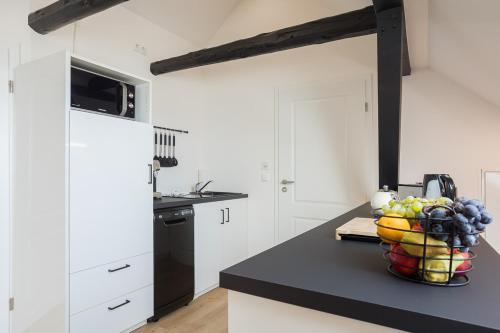 a kitchen with white cabinets and a bowl of fruit on a counter at Familien- und Aparthotel Strandhof in Butjadingen OT Tossens