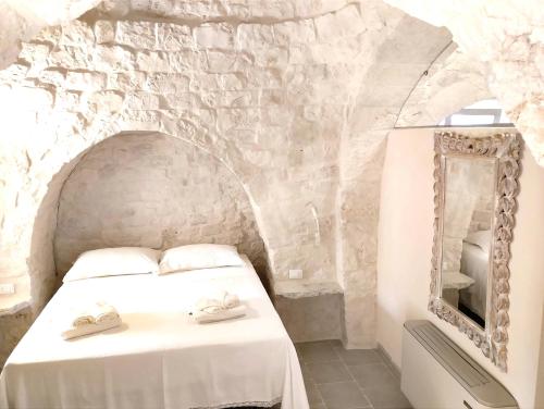 a bedroom with a white bed and a mirror at Trulli Ritunno Piccolo in Locorotondo