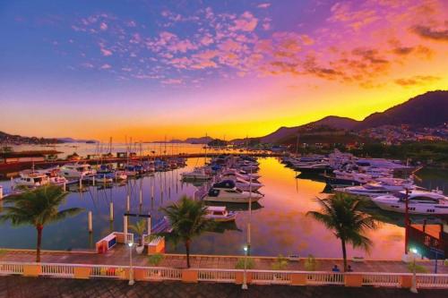 einen Yachthafen mit Booten im Wasser bei Sonnenuntergang in der Unterkunft Apartamento ao lado do shopping Piratas Angra dos Reis in Angra dos Reis