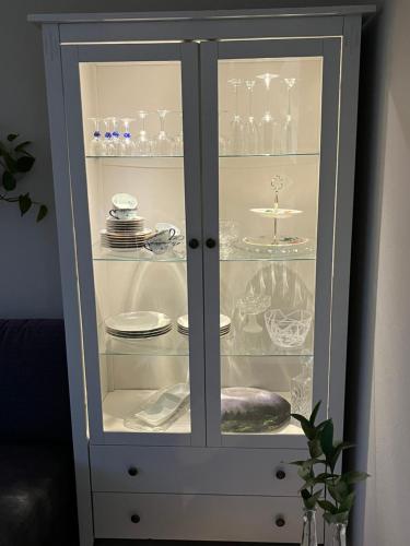 a white cabinet with plates and dishes in it at Lena Apartment Tromsø in Kvaløya