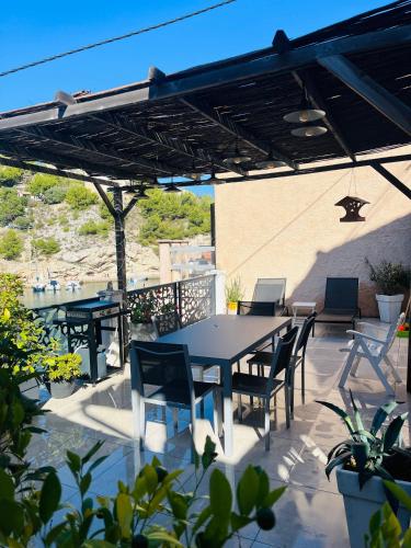 un patio avec une table et des chaises sous une pergola dans l'établissement Cabanon vue mer L ilette Niolon Côte bleue, à Le Rove