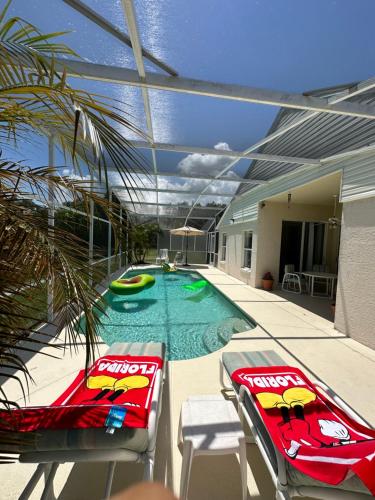 a swimming pool with two red chairs and a swimming poolvisor at Private pool with a beautiful view overlooking the lake! Near Disney - Universal in Kissimmee