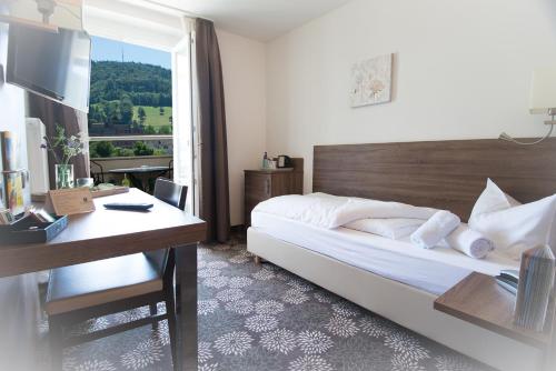 a bedroom with a bed and a desk and a window at Brutsches Rebstock in Laufenburg