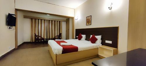 um quarto de hotel com uma cama grande com almofadas vermelhas em Sapphire luxury Suites em Ooty