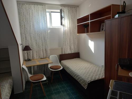 a small room with a bed and a desk and chairs at Kuća za odmor sa 3 spavaće sobe in Kragujevac