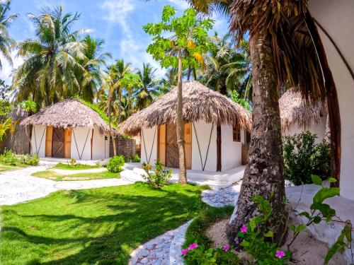 a resort with two huts and a palm tree at Vista Mare Beach House in Tierra Bomba