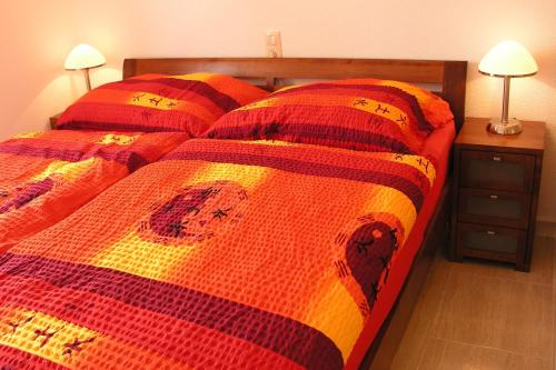 a bedroom with a bed with a red and orange comforter at Duplex apartment Martina - Cumbre del Sol, Benitachell in Cumbre del Sol