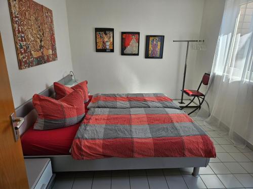 - une chambre dotée d'un lit avec une couverture rouge et grise dans l'établissement Komfortables 3-Zimmer Apartment in Schwetzingen zwischen Mannheim und Heidelberg, à Schwetzingen