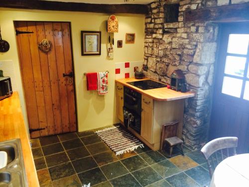 a kitchen with a stove and a stone wall at Low Nook Farm Holiday Cottage in Brampton