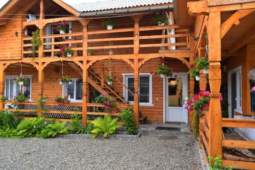 a wooden house with flowers in front of it at Casa Vladicu in Breb