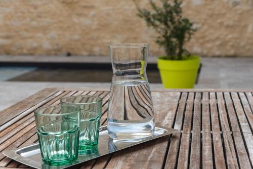 a glass vase and three glasses on a tray on a table at La Petite Cour in Villiers-sous-Grez