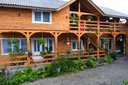 a wooden house with a fence and flowers on it at Casa Vladicu in Breb