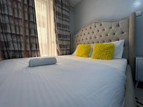 - une chambre avec un grand lit blanc et des oreillers jaunes dans l'établissement Nyumbani Studio, à Nairobi