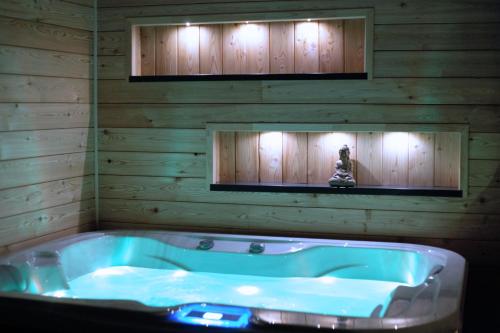 eine Badewanne in einem Zimmer mit einer Holzwand in der Unterkunft Au Plaisir Vosgien in Raon-lʼÉtape