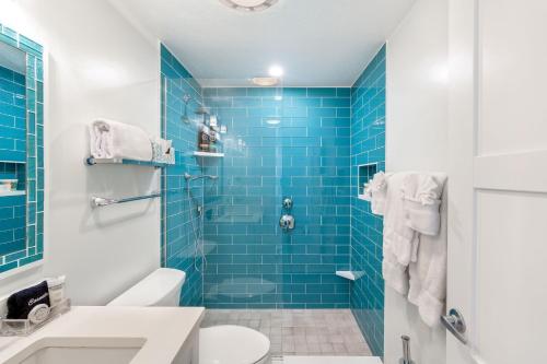 a blue tiled bathroom with a toilet and a shower at Villas of the Galleon #6 in Seven Mile Beach