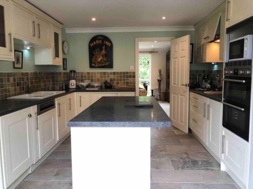 eine große Küche mit weißen Schränken und schwarzen Geräten in der Unterkunft A magical countryside retreat in New Alresford