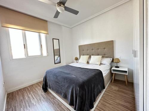 um quarto branco com uma cama grande e uma janela em Arenales del Sol Beach Apartment em Arenales del Sol