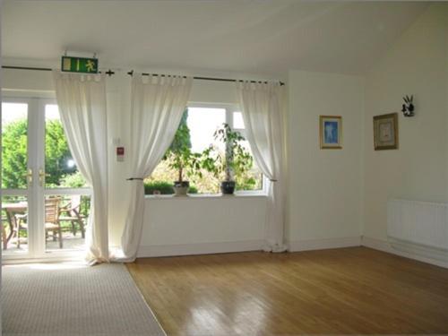 una sala de estar vacía con ventana y cortinas en Robin Hill House Heritage Guest House en Cobh