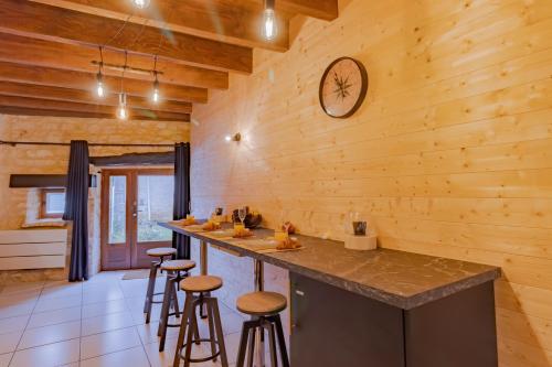 a kitchen with wooden walls and a counter with stools at Le Chalet in Saint-Pardoux-la-Rivière