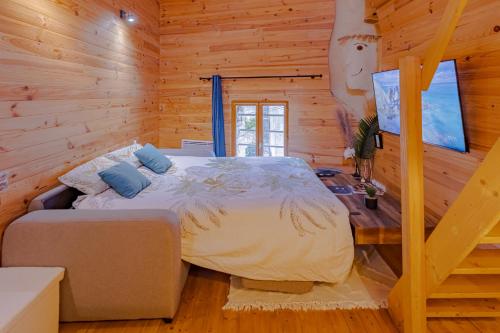 1 dormitorio con 1 cama en una cabaña de madera en Le Chalet Gîte de Dordogne, en Saint-Pardoux-la-Rivière